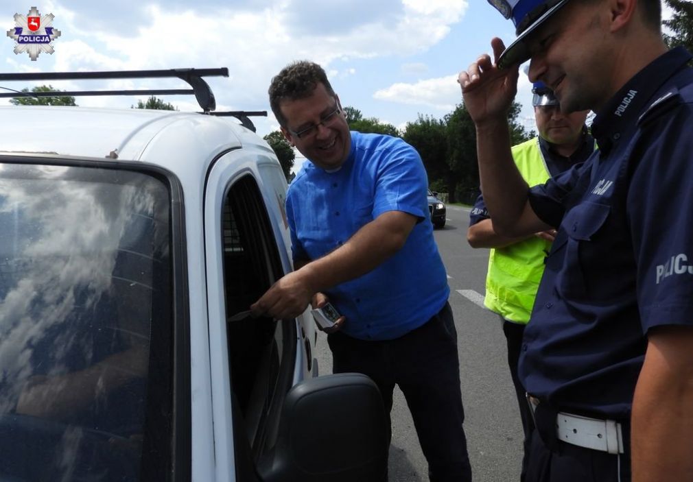 fot. kapelan policjantów ks. Sylwester Zwolak wręcza obrazek Św. Krzysztofa kierującemu pojazdem, obok policjanci z ruchu drogowego